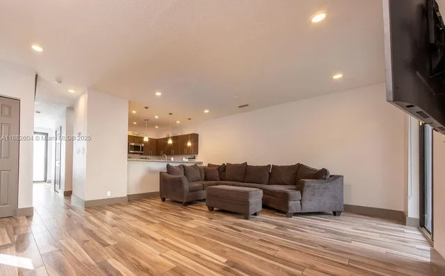 a living room with furniture a flat screen tv and kitchen view