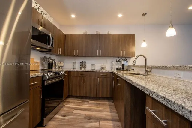 a kitchen with stainless steel appliances granite countertop a sink stove microwave and refrigerator