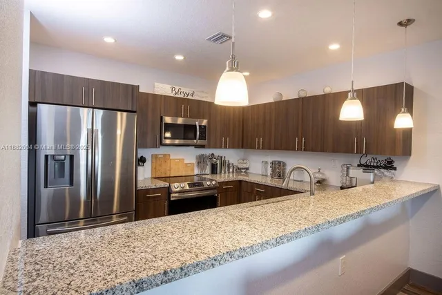 a kitchen with stainless steel appliances granite countertop a sink refrigerator and microwave
