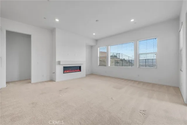 an empty room with a ceiling fan and carpet