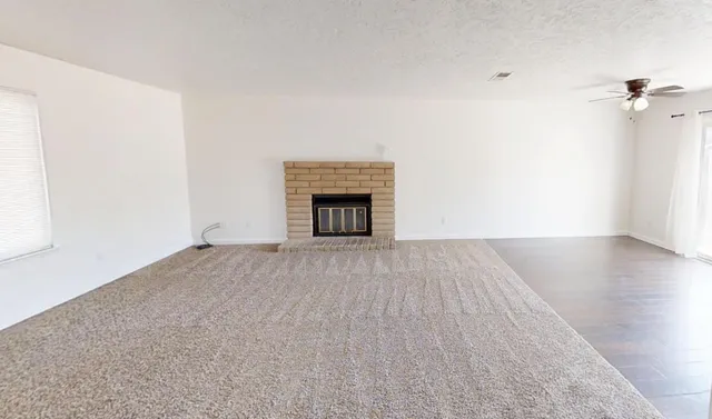 an empty room with wooden floor fireplace and windows