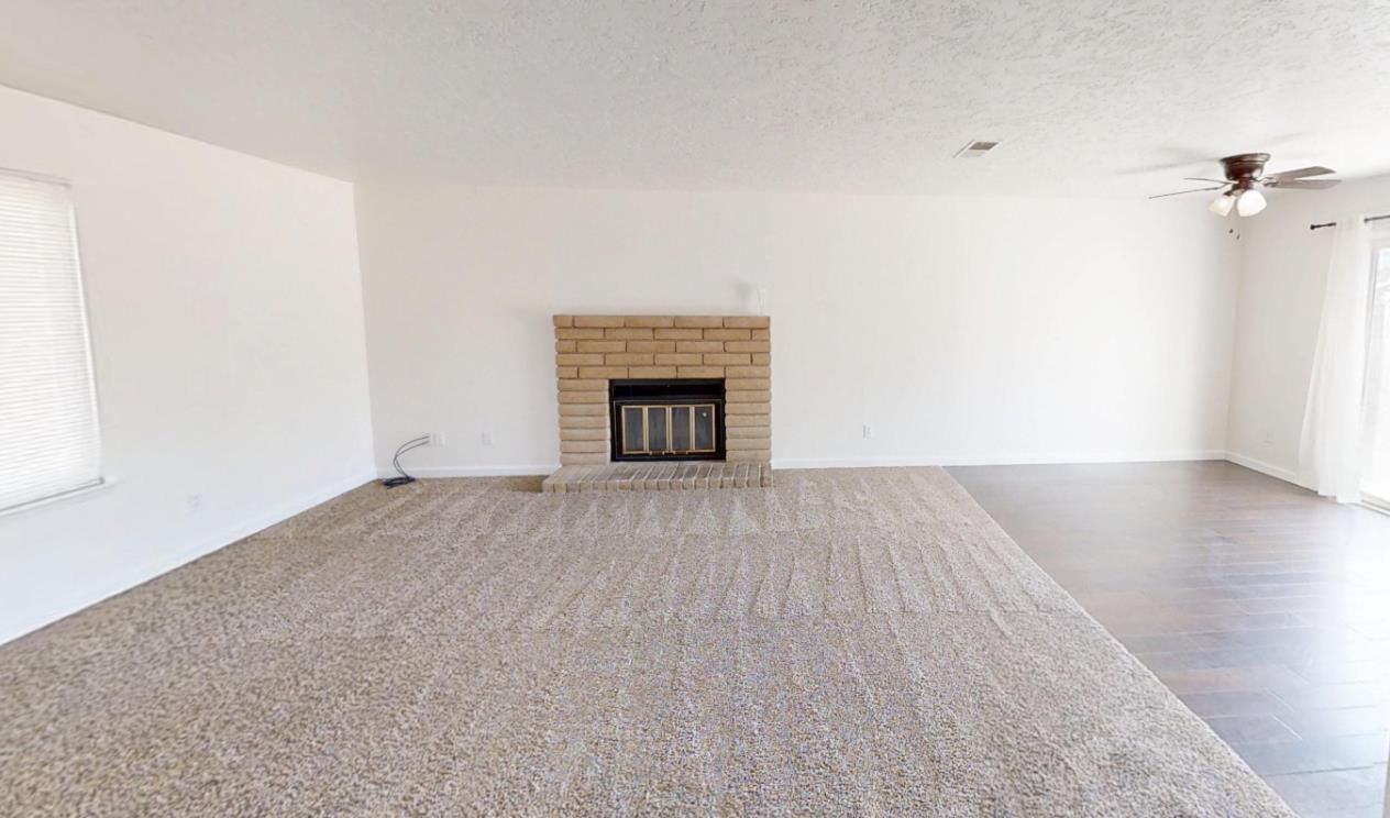 495 Pacific Street Coalinga, CA 93210 - Photo 3 of 33 an empty room with wooden floor fireplace and windows