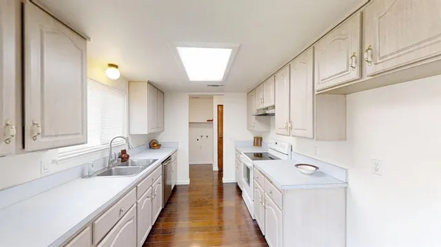 a view of a kitchen with kitchen island white wooden cabinets and stainless steel appliances