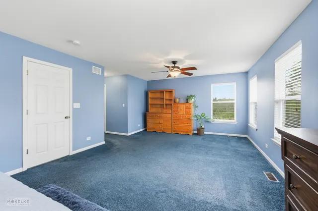 an empty room with windows and ceiling fan