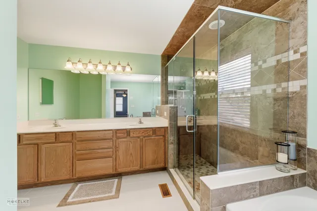 a spacious bathroom with a glass shower sink and mirror