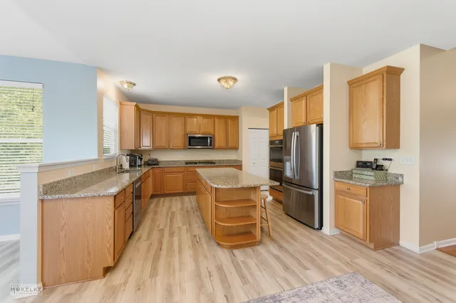 a kitchen with stainless steel appliances granite countertop a refrigerator a stove and a sink with cabinets