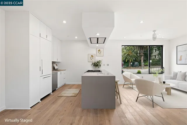 a living room with kitchen island stainless steel appliances furniture a large window and wooden floor