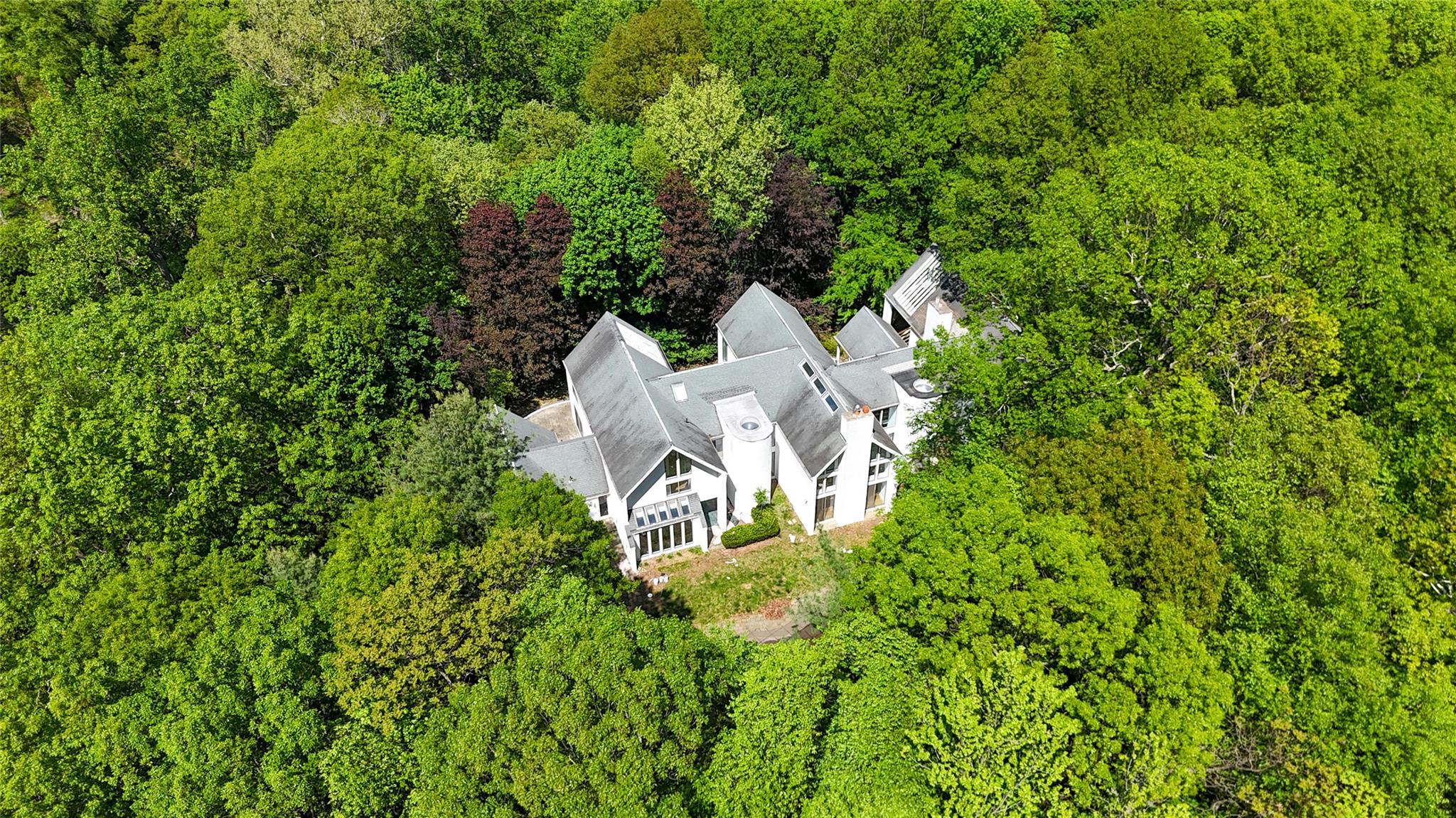 a view of a house with a small yard and large trees