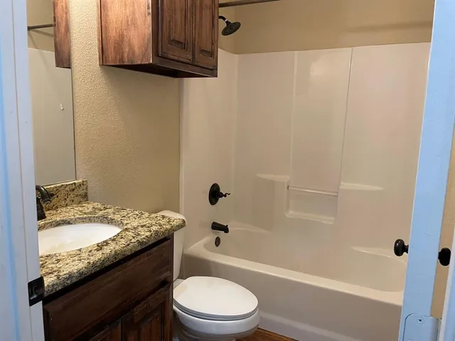 a bathroom with a granite countertop sink toilet and shower