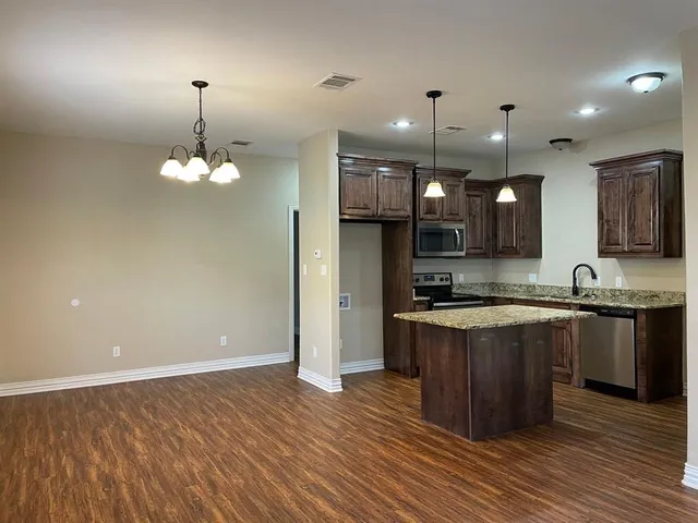 a large kitchen with stainless steel appliances granite countertop a sink a stove and a wooden floors