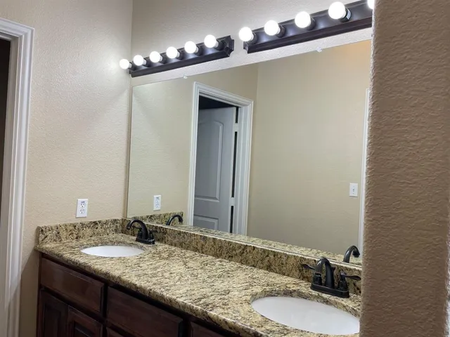 a bathroom with a granite countertop sink and a mirror