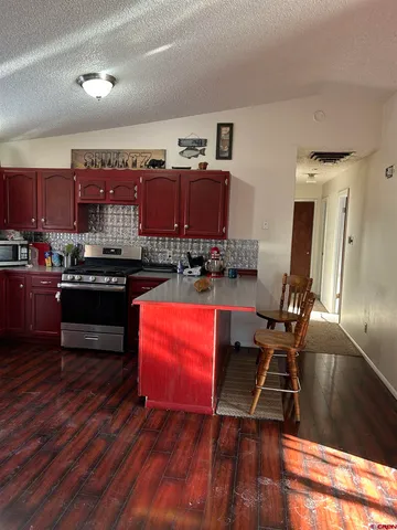 a kitchen with stainless steel appliances wooden floors and a view of living room