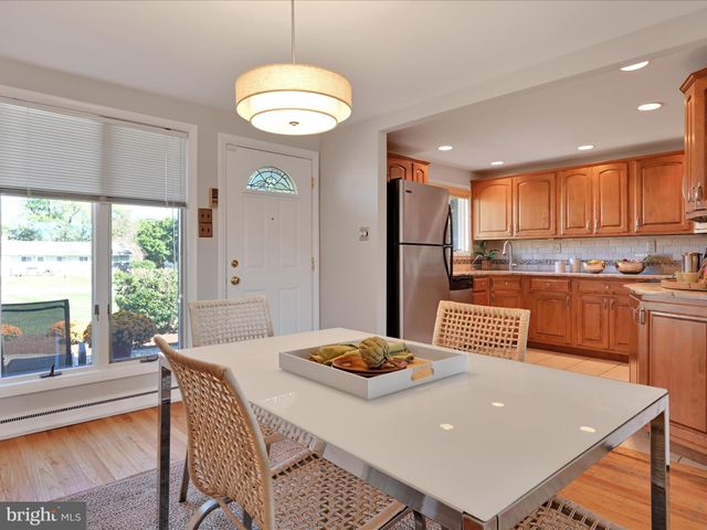 a living room with stainless steel appliances granite countertop a table chairs and a refrigerator