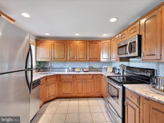 a kitchen with stainless steel appliances granite countertop a refrigerator a sink dishwasher a stove top oven and cabinets