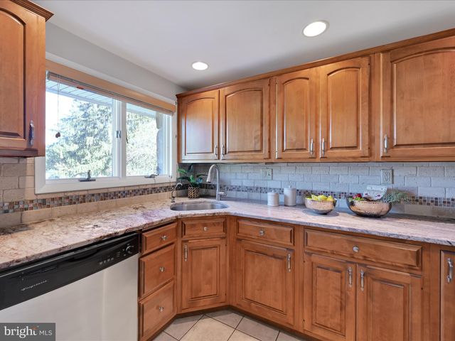a kitchen with stainless steel appliances granite countertop white cabinets sink and window