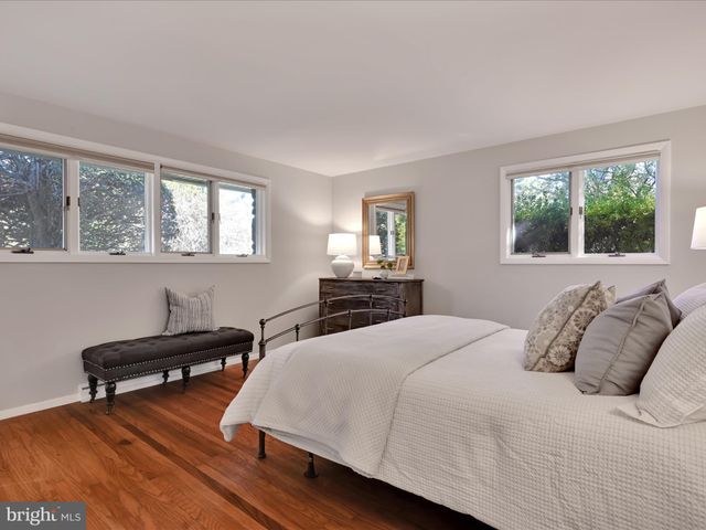 a bedroom with a bed a dresser and windows