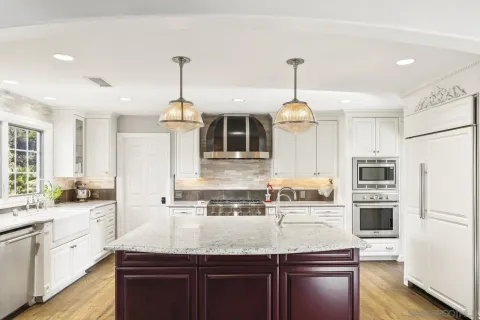 a kitchen with kitchen island granite countertop a stove a sink a oven and wooden cabinets with wooden floor