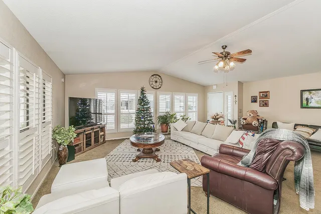a living room with furniture ceiling fan and a large window