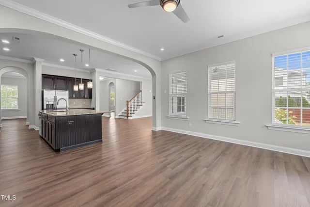 an open kitchen with a refrigerator and wooden floor