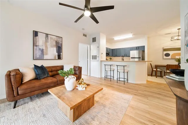 a living room with furniture a kitchen view and a wooden floor