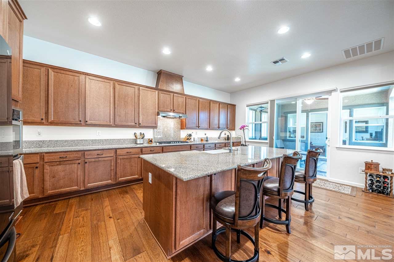 9845 Shadowless Trail Reno, NV 89521 - Photo 11 of 40 a kitchen with stainless steel appliances granite countertop wooden floor a stove a sink dishwasher and cabinets with wooden floor