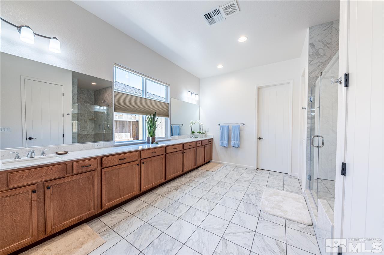 9845 Shadowless Trail Reno, NV 89521 - Photo 17 of 40 a large bathroom with a double vanity sink a mirror and a shower