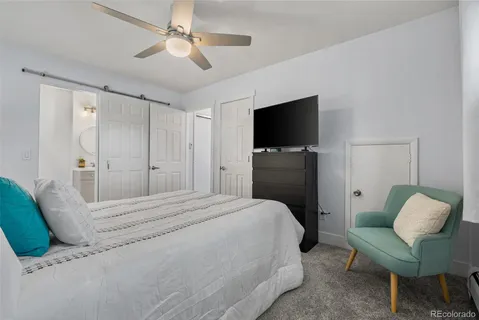 a bedroom with a bed a chair and flat screen tv