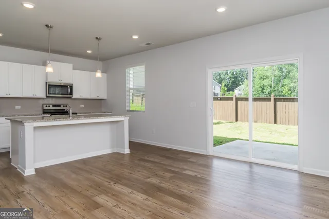 a kitchen with stainless steel appliances granite countertop a refrigerator a sink dishwasher a stove and white cabinets with wooden floor