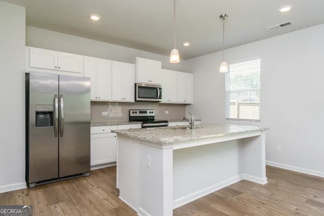 a large kitchen with kitchen island a counter space a sink appliances and cabinets