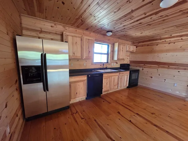 a kitchen with stainless steel appliances granite countertop wooden floors and white cabinets