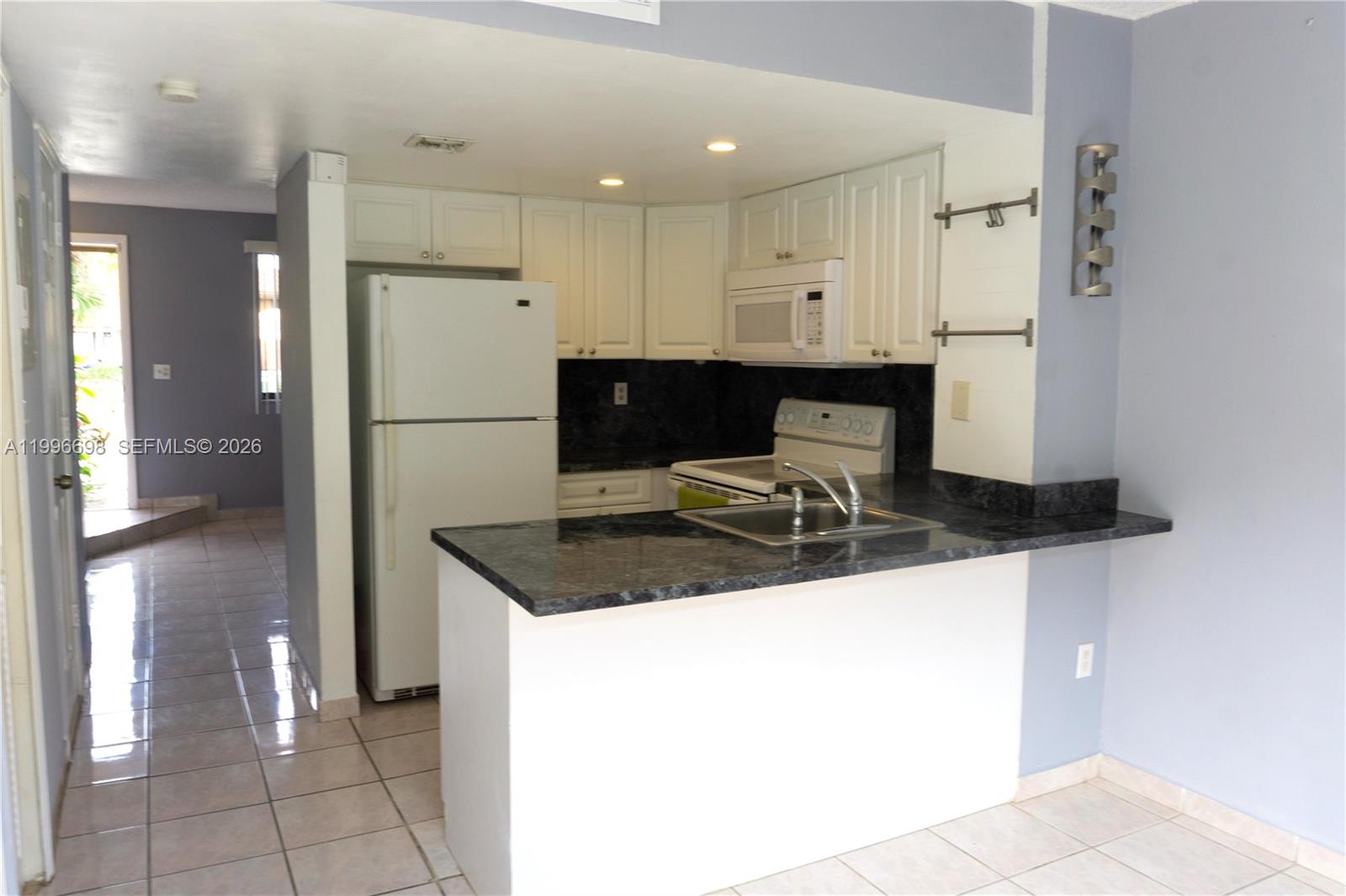 1911 Southwest 107th Avenue, Unit 1006 Miami, FL 33165 - Photo 5 of 17 a kitchen with stainless steel appliances granite countertop a sink and a refrigerator