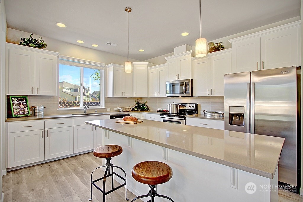 3008 Stephanie Loop Northeast Lacey, WA 98516 - Photo 3 of 5 a kitchen with stainless steel appliances granite countertop a sink a stove a refrigerator cabinets and chairs