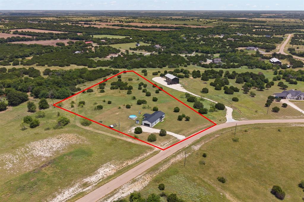 1031 Augustus Court Rio Vista, TX 76093 - Photo 26 of 30 Expansive acreage featuring a single-story residence with an attached garage, a separate outbuilding, and varied tree coverage