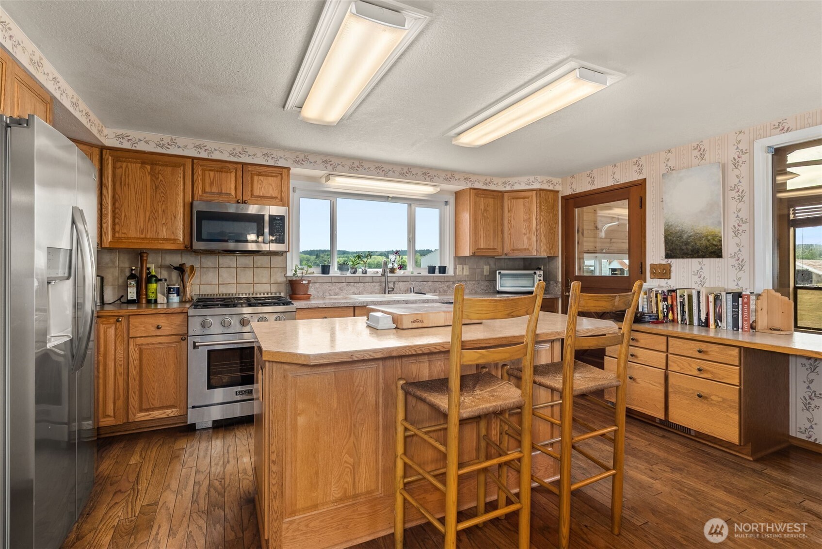 627 Wynoochee Valley Road Montesano, WA 98563 - Photo 25 of 40 a kitchen with stainless steel appliances kitchen island granite countertop a stove top oven a sink a refrigerator cabinets and dining table