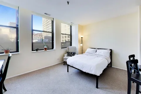 a bedroom with a bed and large windows