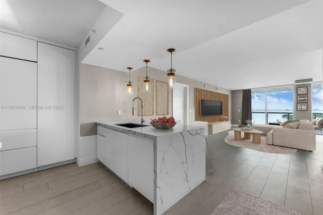 a living room with stainless steel appliances kitchen island furniture and a flat screen tv