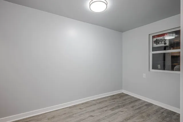 a view of an empty room with wooden floor and windows