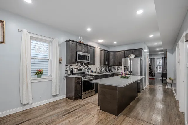 a large kitchen with stainless steel appliances granite countertop a stove refrigerator and a sink