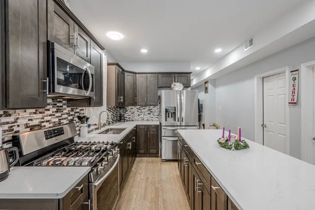 a kitchen with stainless steel appliances kitchen island granite countertop a sink stove and refrigerator