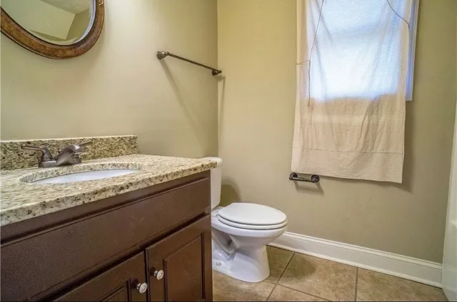 a bathroom with a granite countertop toilet sink and mirror