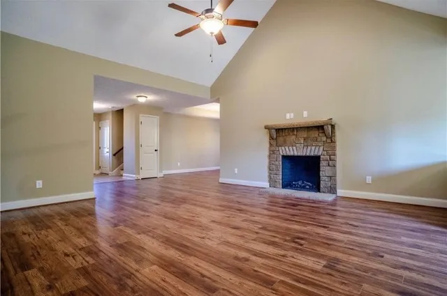 a view of an empty room with wooden floor a fireplace and a window