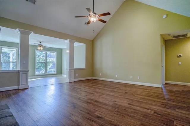 a view of an empty room with window and wooden floor