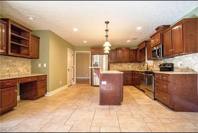 a kitchen with kitchen island granite countertop wooden cabinets and stainless steel appliances