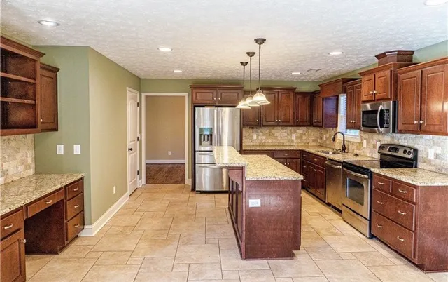 a large kitchen with stainless steel appliances kitchen island granite countertop a stove and a sink