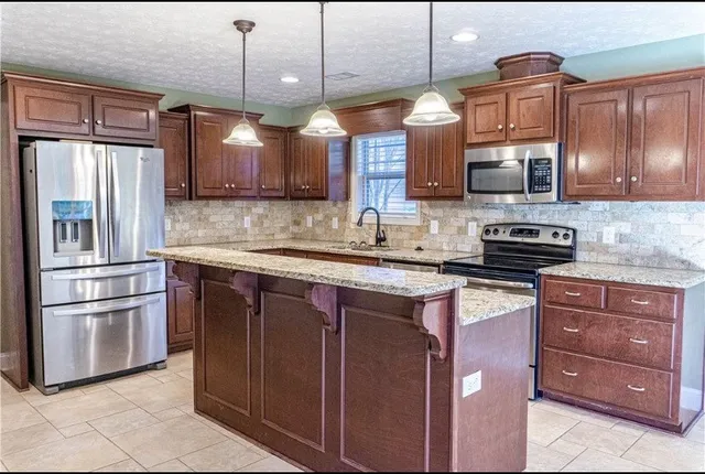a kitchen with stainless steel appliances granite countertop a refrigerator a stove a sink and a microwave