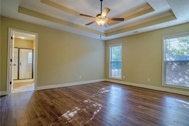 an empty room with wooden floor and a ceiling fan