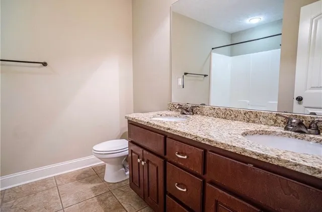 a bathroom with a granite countertop sink a toilet and a mirror
