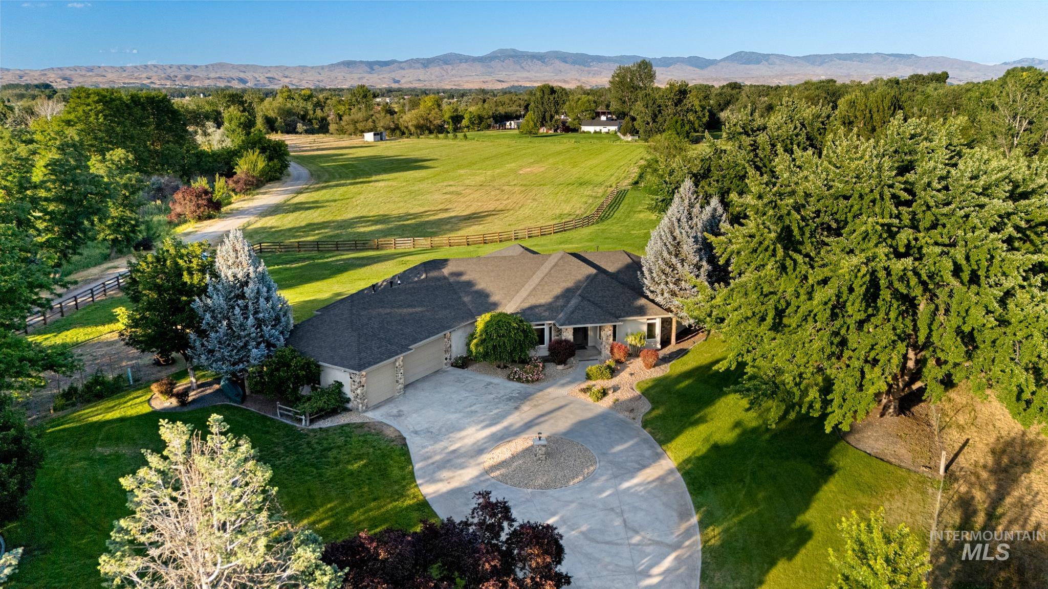 2050 Artesian Road Eagle, ID 83616 - Photo 4 of 49 Expansive property featuring a single-story residence with a multi-car garage, paved circular driveway, mature trees, and a large grassy field