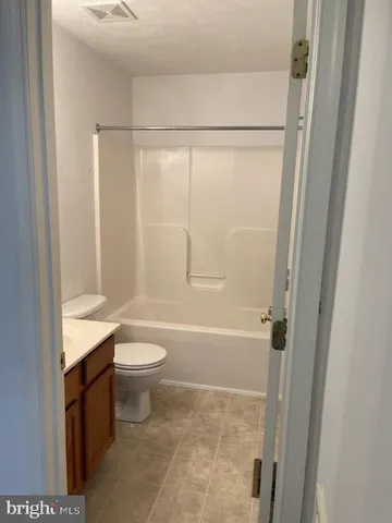 a bathroom with a granite countertop bathtub shower sink vanity and toilet