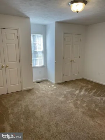 a view of an empty room with window and closet area